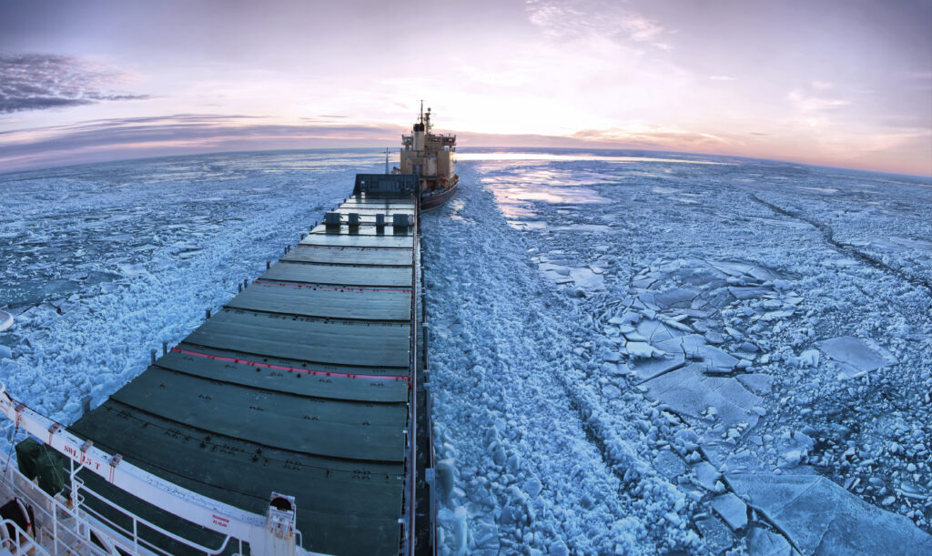 Icebreaker towing cargo ship through thick ice-field.